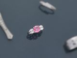 quelques diamants roses et blancs sont posés sur une surface noire