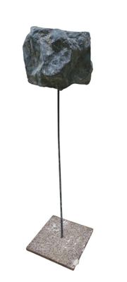 sculpture représentant un rocher posé sur un socle métallique, sur fond blanc