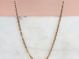une photo du collier à chaîne en or posé sur une surface en marbre