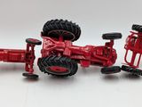 a red toy tractor that is sitting on a white surface