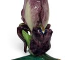 a purple flower sitting on top of a green leaf
