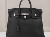 un sac à main en cuir noir posé sur une table blanche