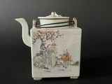 a white tea pot with a painting on it