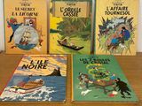 Quatre livres pour enfants sont posés sur une table devant un mur blanc