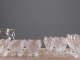 bottles and glasses sitting on a table with a pitcher in the background