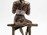a bronze statue of a woman sitting on a bench