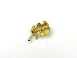 a close up of a gold flower brooch on a white surface