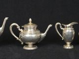 three silver teapots and a coffee pot on a black background