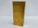 a gold vase that is sitting on a white surface