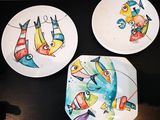 trois assiettes ornées de poissons peints, posées sur une table