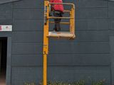 a man that is standing on a scissor in front of a building