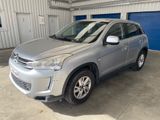 un SUV argenté garé dans un garage dont la porte est bleue