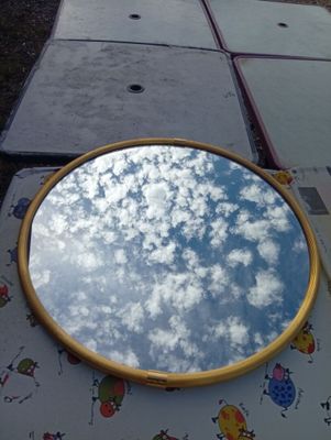 a mirror sitting on a table with a sky reflection in it