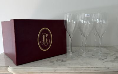 quatre verres à vin posés sur une table, à côté d'une boîte