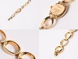 a close up of a gold necklace and bracelet on a white surface