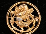 une image représentant une broche plaquée or ornée d'un dragon