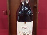the bottle of wine is next to a wooden box on a red surface