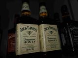 bottles of jack daniels honey sit on a shelf in a bar