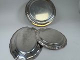 three silver plates with lids on a table with a white background