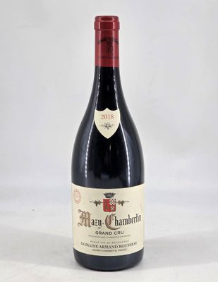 the bottle of red wine is sitting on a white surface