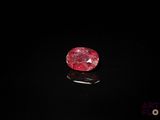 un diamant rouge sur une surface noire dans l'obscurité