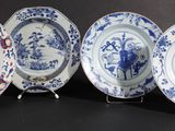 four blue and white plates with designs on them on a black surface