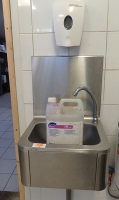 un évier en acier inoxydable avec un distributeur de savon fixé au mur