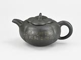 a black teapot with writing on it on a white surface