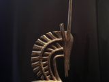 une sculpture en bronze représentant un cheval sur un socle, avec un fond noir