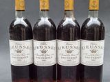 four bottles of wine are lined up on a table