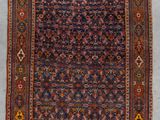 un tapis persan ancien présentant un motif géométrique sur fond bleu