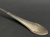 an old spoon with a design on it sitting on a table