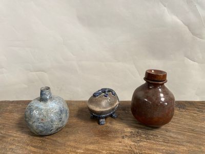 trois vases posés sur une table en bois, avec un mur blanc en arrière-plan