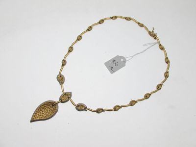 un gros plan d'un collier composé d'une feuille suspendue à une chaîne