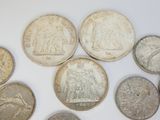 plusieurs types de pièces de monnaie sont disposés sur une surface blanche