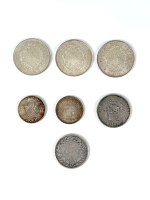 six different coins are arranged in a row on a white surface