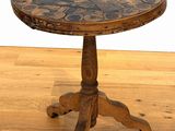 une petite table en bois avec un plateau en faïence, posée sur un parquet