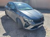 La voiture grise est garée sur le gravier près d'un bâtiment.
