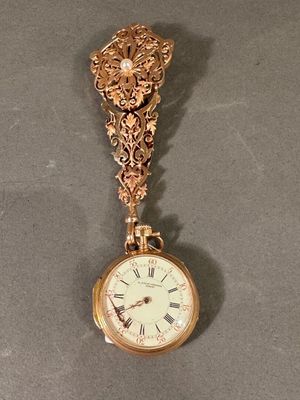 une horloge en or suspendue à une chaîne au mur