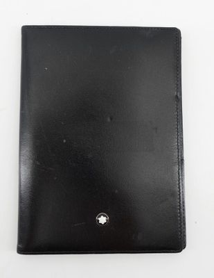 un gros plan d'un portefeuille en cuir noir posé sur une surface blanche
