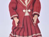 une poupée qui porte une robe rouge et un chapeau