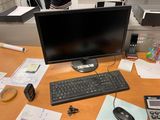 a computer monitor and keyboard on a desk with papers and calculator