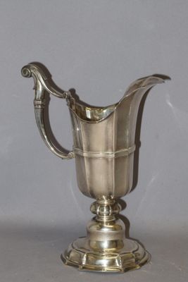 an antique silver plated pitcher on a pedestal with a handle