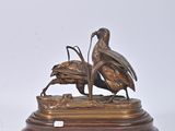 a bronze statue of two birds on a wooden base
