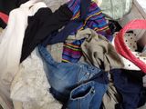 a suitcase full of clothes and clothes sitting on a bed