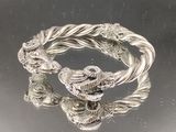 deux bracelets en argent sur une surface noire avec un fond argenté