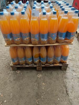 Plusieurs bouteilles de jus d'orange sont empilées sur une palette