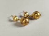 a close up of a pair of gold earrings on a white surface
