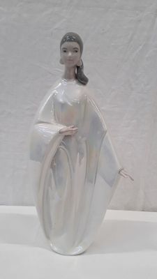 a figurine of a woman in a white dress on a table