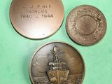 two coins and a coin with a picture of a ship on it